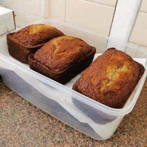 Three loaves of banana bread sitting in an open container.