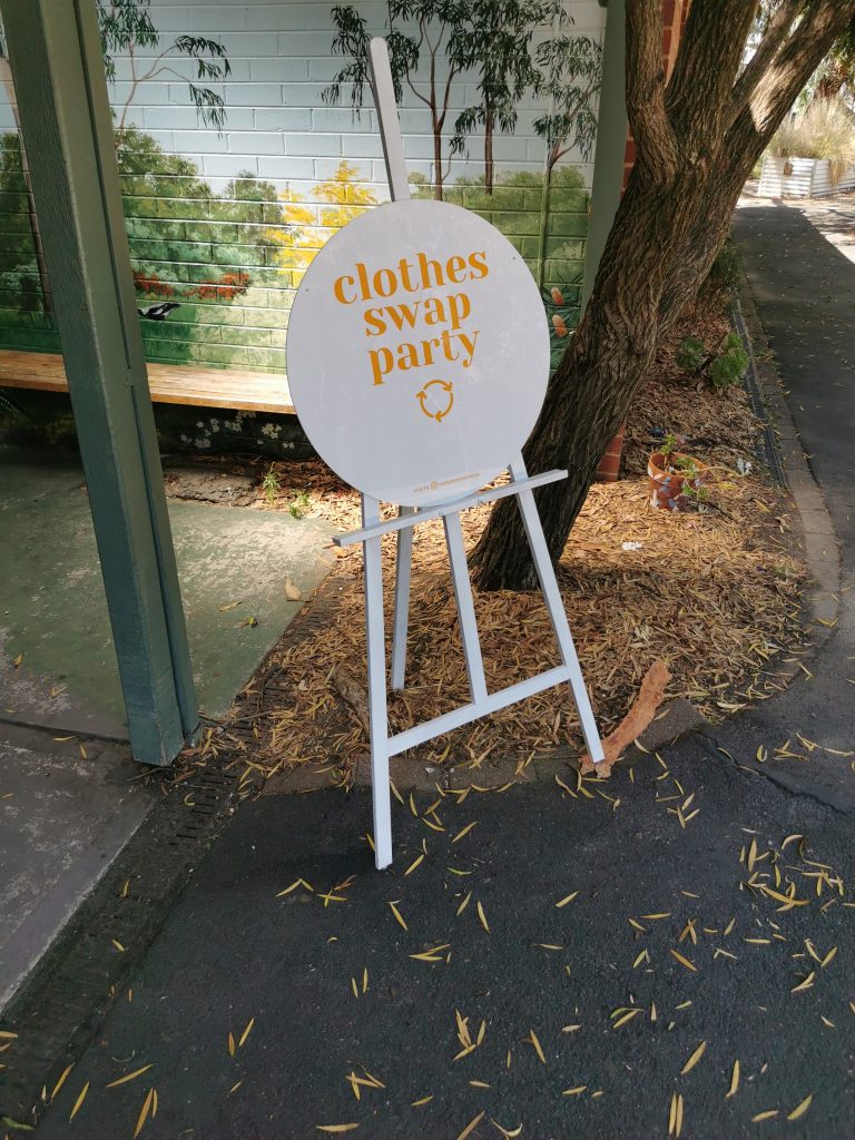A white circular sign with 'clothes swap party' in yellow.